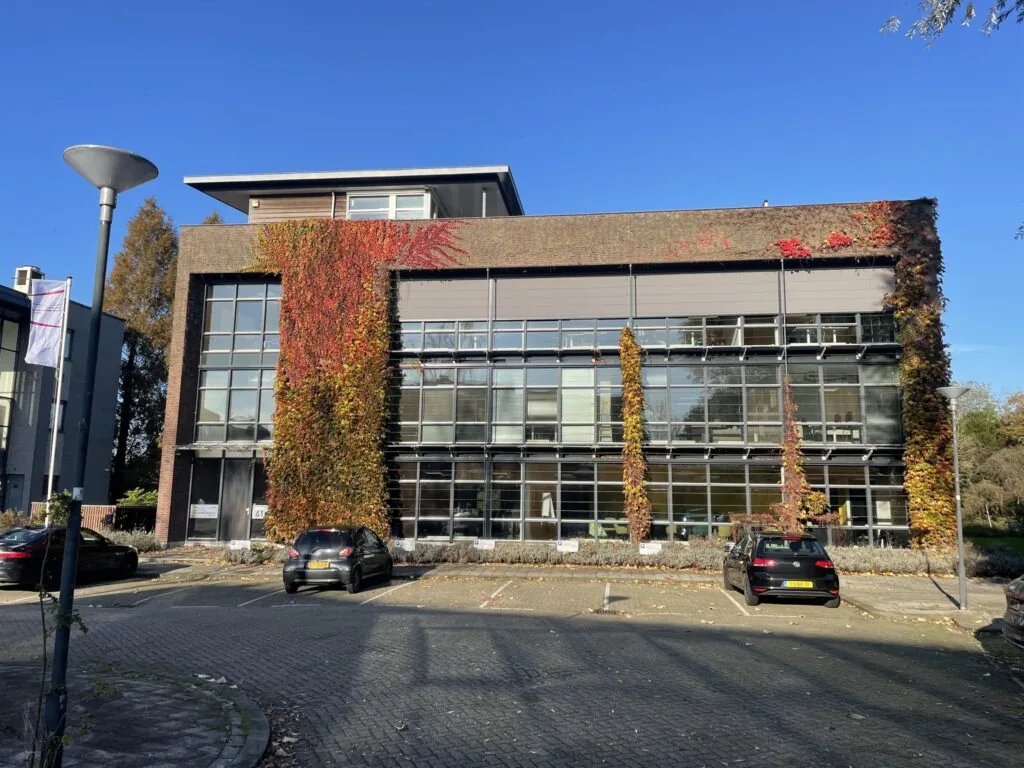 Kantoorgebouw aan de Jan Leentvaarlaan met grote ramen, begroeid met herfstkleurige klimop.